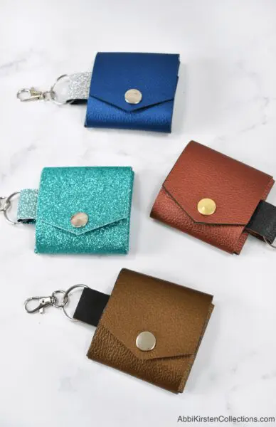 Four DIY faux leather photo keychains in varying colors on a marble counter.