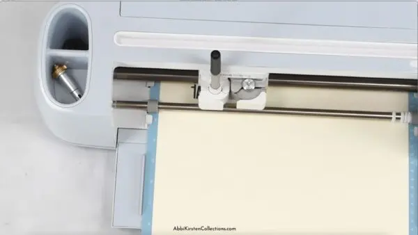 A pen writing on vanilla colored paper using a Cricut.