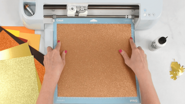 Bronze glitter card stock being loaded into the Cricut.  