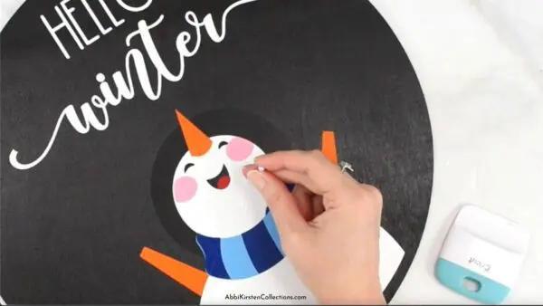 The image shows Abbi's hand using a sewing pin to remove air bubbles in vinyl for a smooth application. 