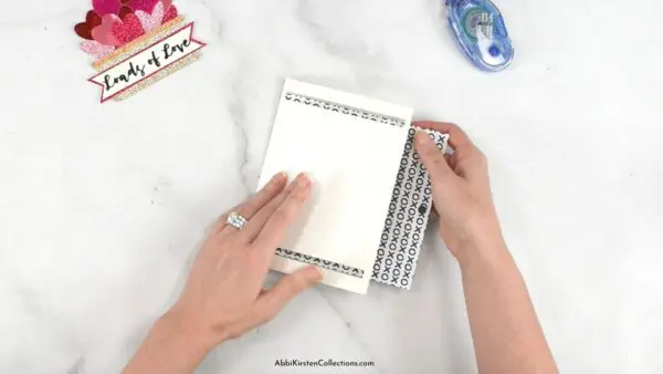 A card insert is added to a white glitter card that was cut with Cricut for Valentine's Day. A cutout of glitter hearts in a basket is in the background.