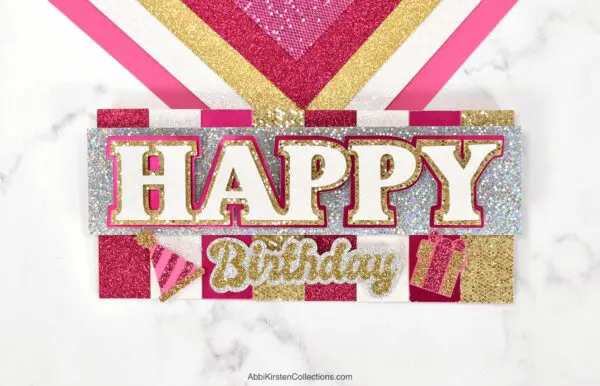 The image shows a handmade happy birthday card. These layered Cricut cards are easy for beginners. 