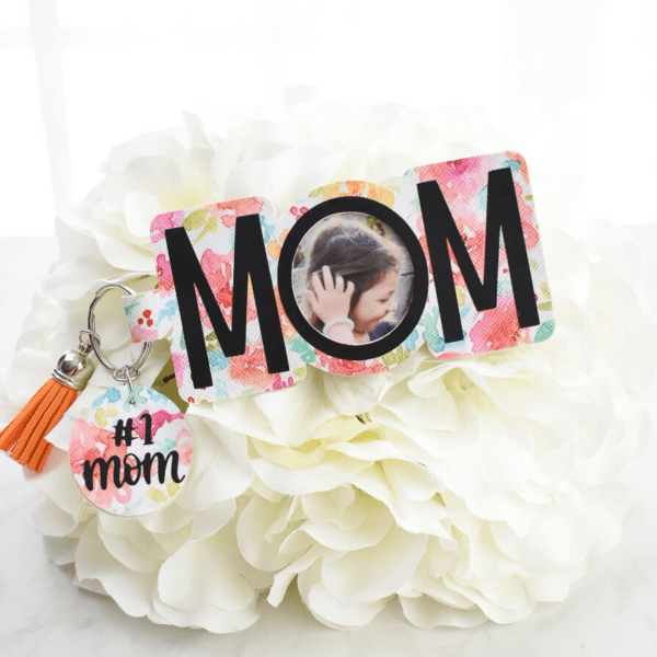 The image shows a DIY photo keychain made from colorful floral faux leather with a personalized picture that says Mom.
Get the free SVG file.