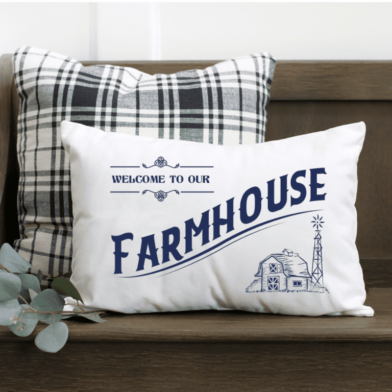 Welcome to our farmhouse free SVG cut file shown on a while pillow with dark blue vinyl.