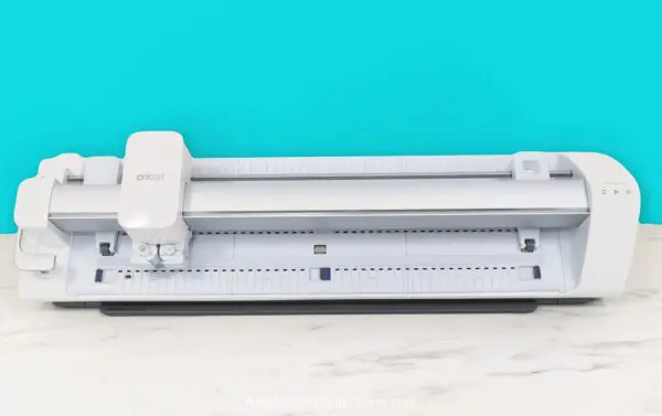 Cricut Venture machine on a white desk with a bright blue background