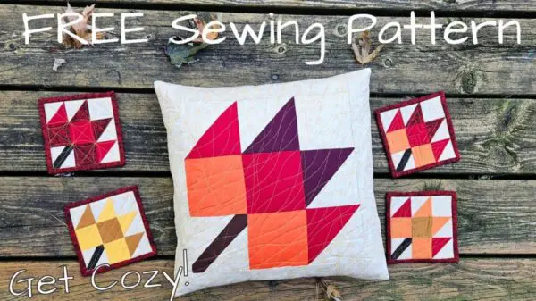 Pillow with maple leaf pattern in orange, red, and purple colors on white background.