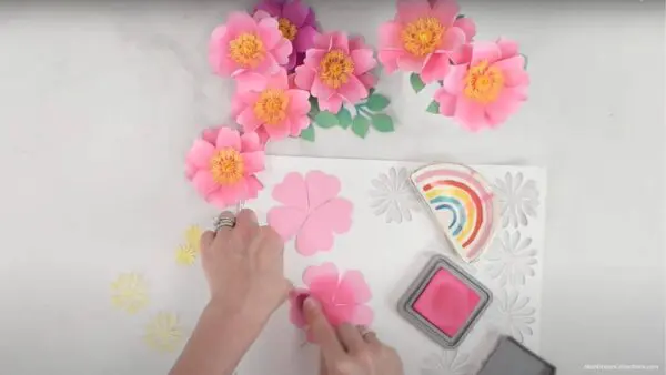 Pink distress ink being added to a paper flower petal