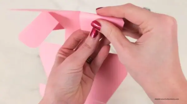 Hands folding the score lines for the treat box papercraft