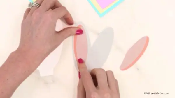 Gluing two pink bunny ears pieces to one of bunny ears