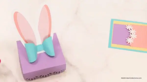 pink bunny ears, blue bow, and purple lid