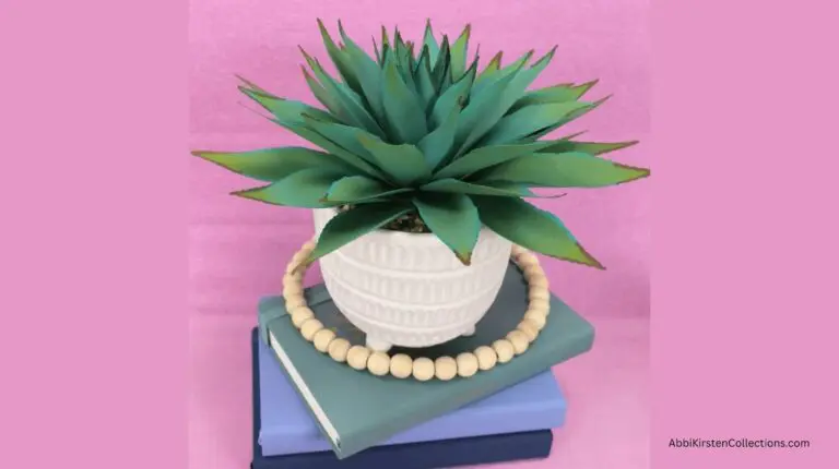 blue paper agave plant in pot sitting on books