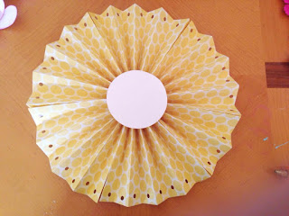 The rosette fan made of yellow and white scrapbooking paper has a 3-inch white circle on it's center. 