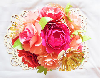 A brightly colored bouquet made of cheerful paper flowers on a lace doily. 