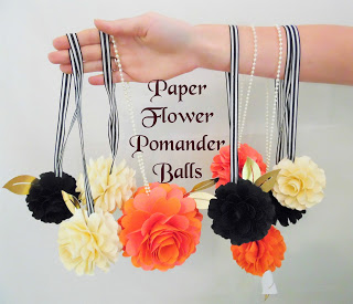 Abbi Kirsten has paper flowers hanging from her outstretched arm with ribbon. The text in the center reads, "Paper flower pomander balls."