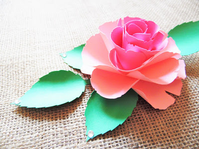 The paper Ruby Rose and matching paper greenery sits open on a piece of tan canvas. Paper flowers are easy and fun to make with my templates. 