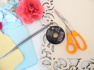 Craft supplies gathered for making a flower wall art craft include mason jar cut-outs, scossors, a paper flower and a decorative wooden frame. 