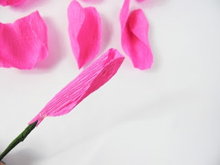 A close-up of the crepe paper rose petal has been curled and adhered to the flower stem. 