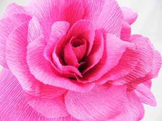 A close-up of the crepe paper rose, as the petals spread out from the tight center, creating a beautiful and gentle paper flower. 