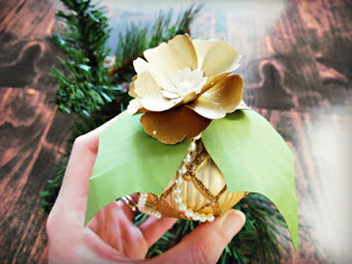 Abbi Kirsten holds a lattice-patterned gold ornament which she has jazzed up with green paper leaves, a small string of pearls and a gold paper flower on top. 
