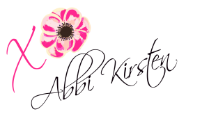 Abbi Kirsten's signature with a pink X and an O made from a flower.
