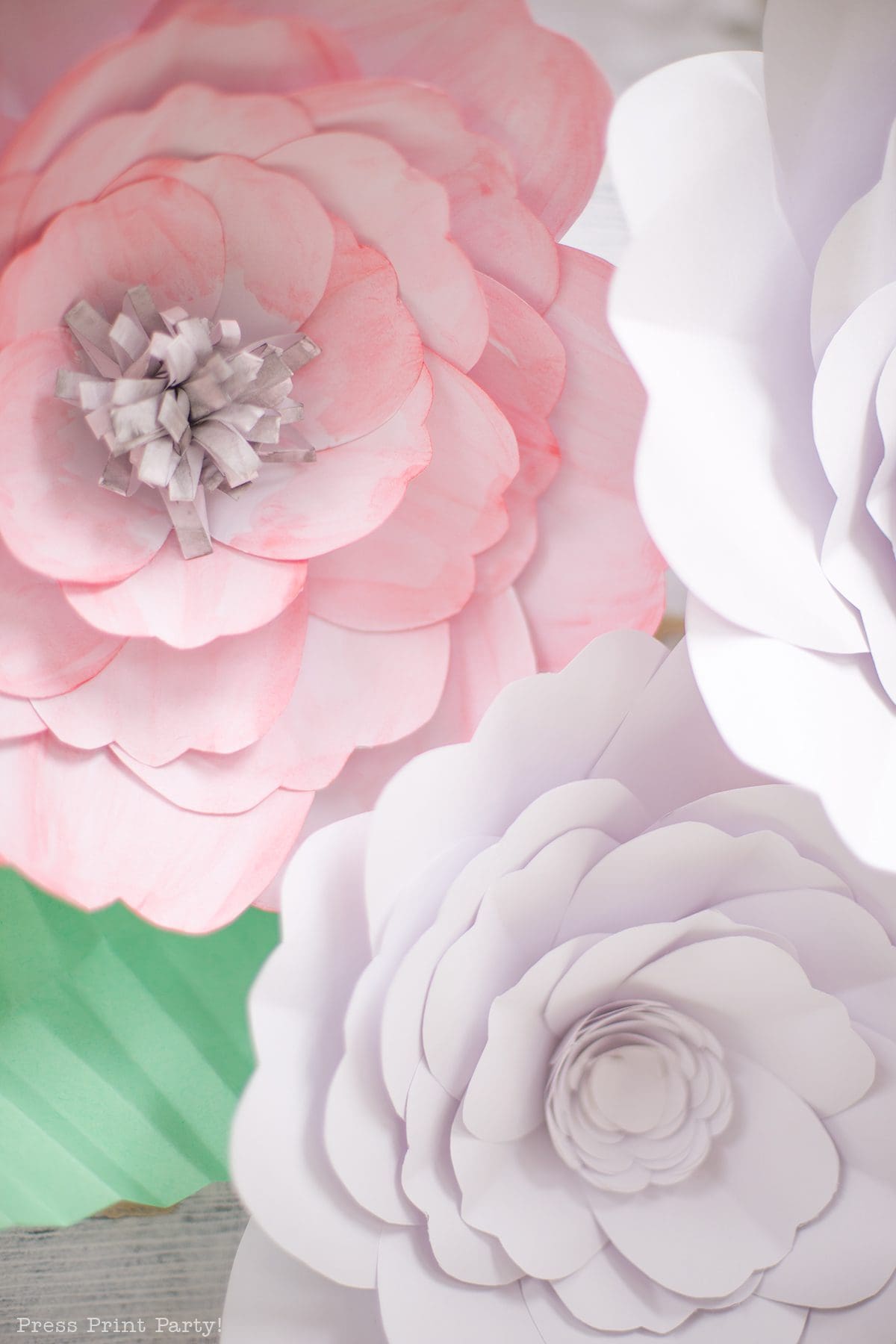 A closeup of blooming paper flowers used as decoration for a shabby chic baby shower. Paper leaves are visible from under a flower. 