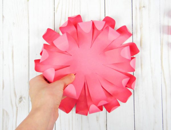 Abbi places a second chrysanthemum flower layer on top of previous pink paper flower layers to create a fuller flower.