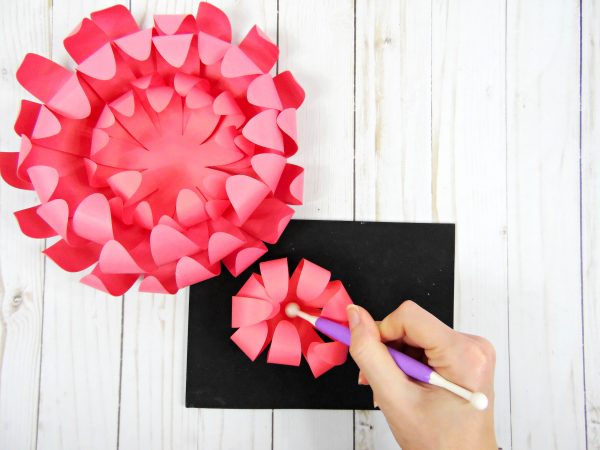 Abbi uses the shaping tool and rolling mat to curl the final Chrysanthemum flower layer inwards, before adding it to the almost-complete pink paper Chrysanthemum flower.