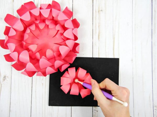 Abbi uses the shaping tool and rolling mat to curl the final Chrysanthemum flower layer inwards, before adding it to the almost-complete pink paper Chrysanthemum flower.