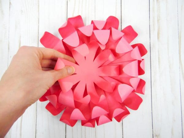 Abbi places the final pink paper Chrysanthemum flower layer on top of the other layers, creating a full paper flower.