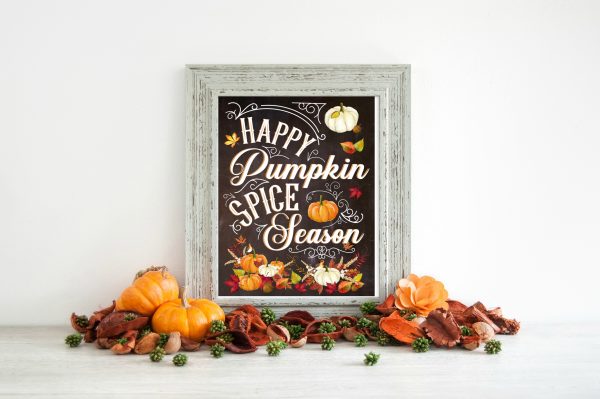 Happy Pumpkin Spice Season is written on black paper decorated with fall staples like pumpkins, gourds and leaves. A gray wooden frame surrounds the free printable. 