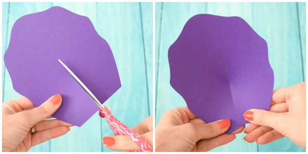 DIY Iris Unicorn Rainbow Flowers instructions for large rainbow paper flowers. Abbi Kirsten's hand shows how to cut a slit on a large purple petal and then how to shape the petal. 