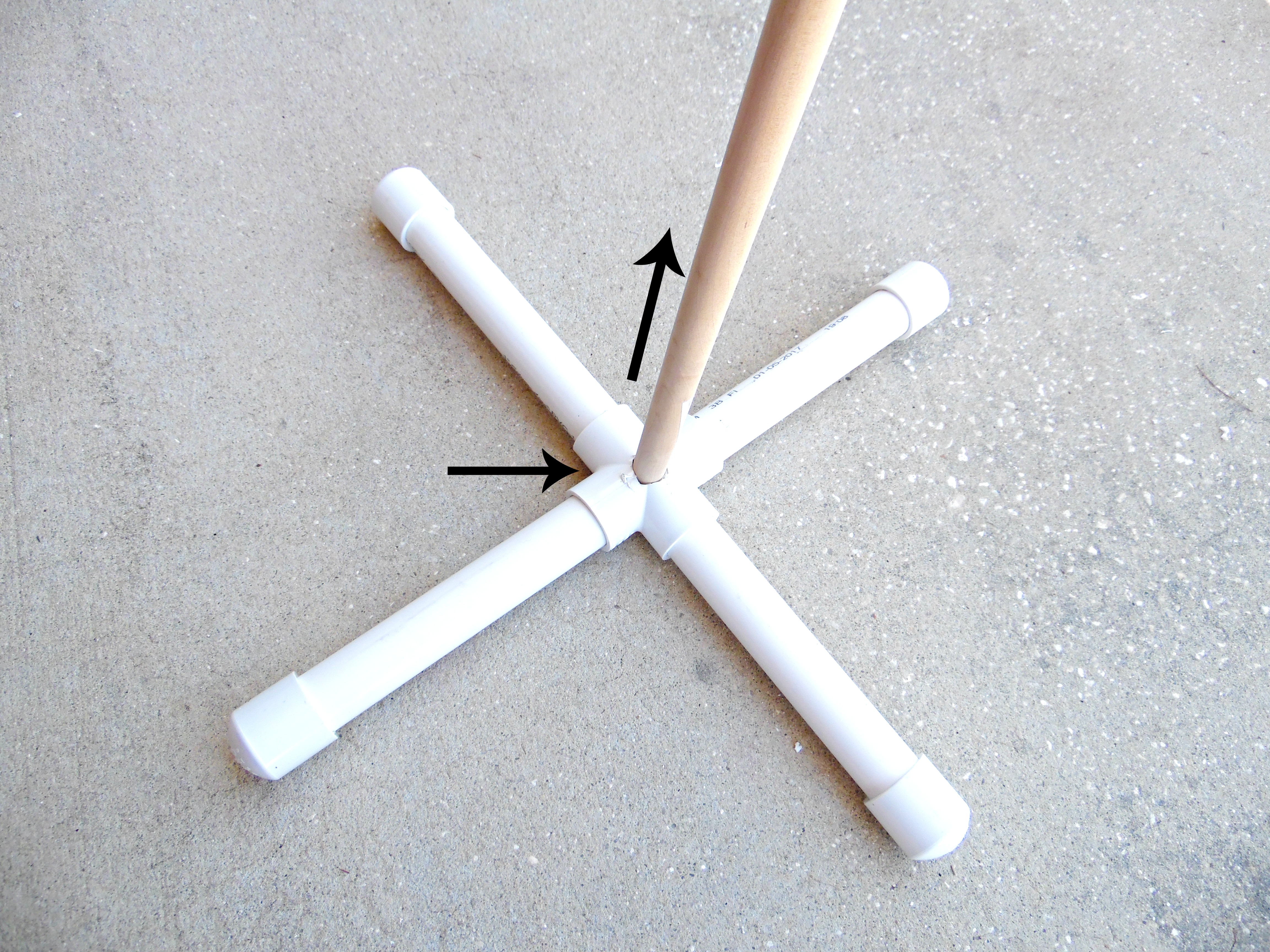 This image shows a plain wooden dowel – the giant paper flower stem – placed in the center of the PVC pipe stand. 