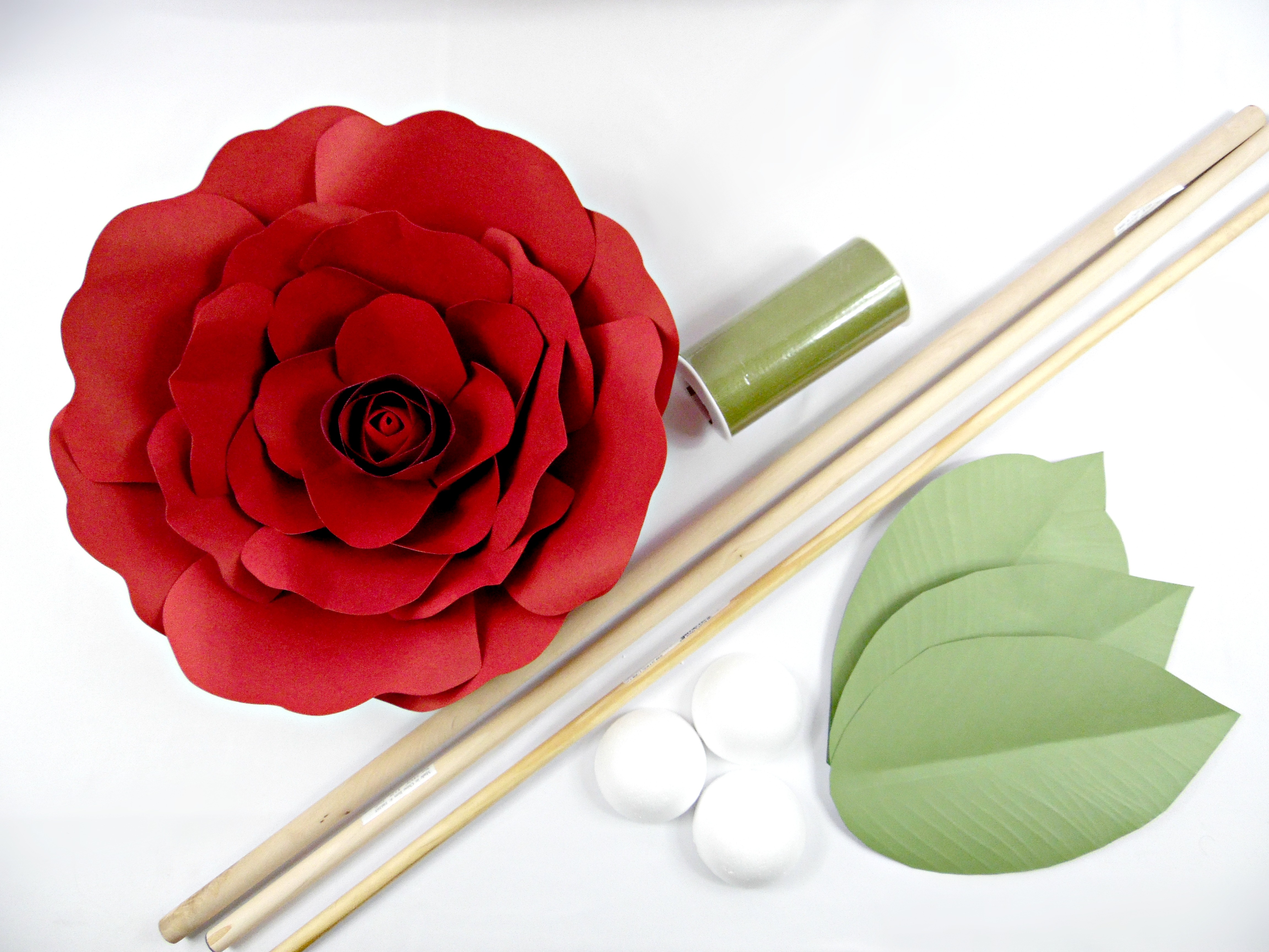All the supplies needed to make giant paper flower stems: paper flower, leaves, dowel, foam balls, and tulle or paint. 