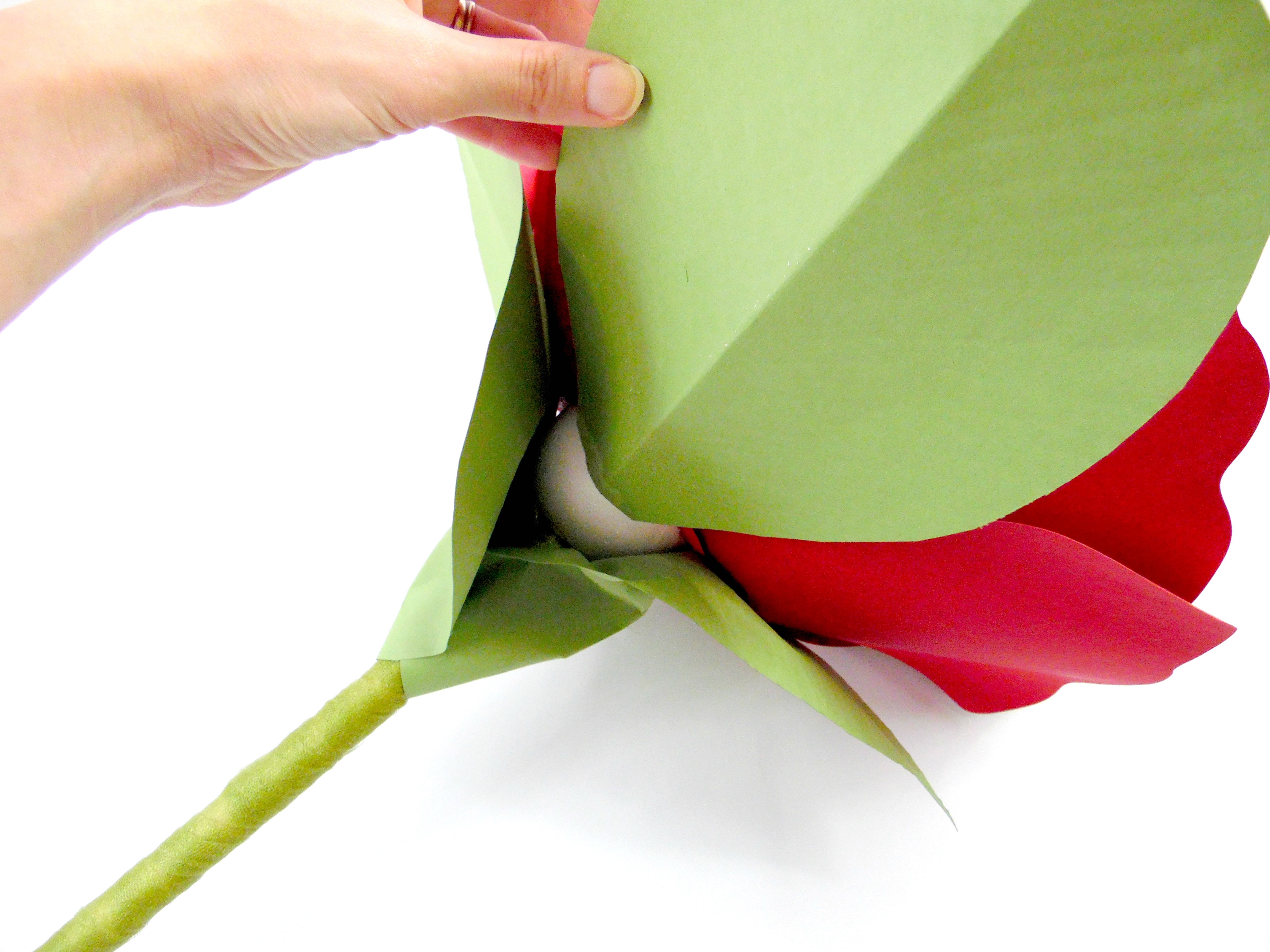 To hide the foam ball, attach more paper leaves to the giant paper flower stem surrounding the foam ball flower head base.  