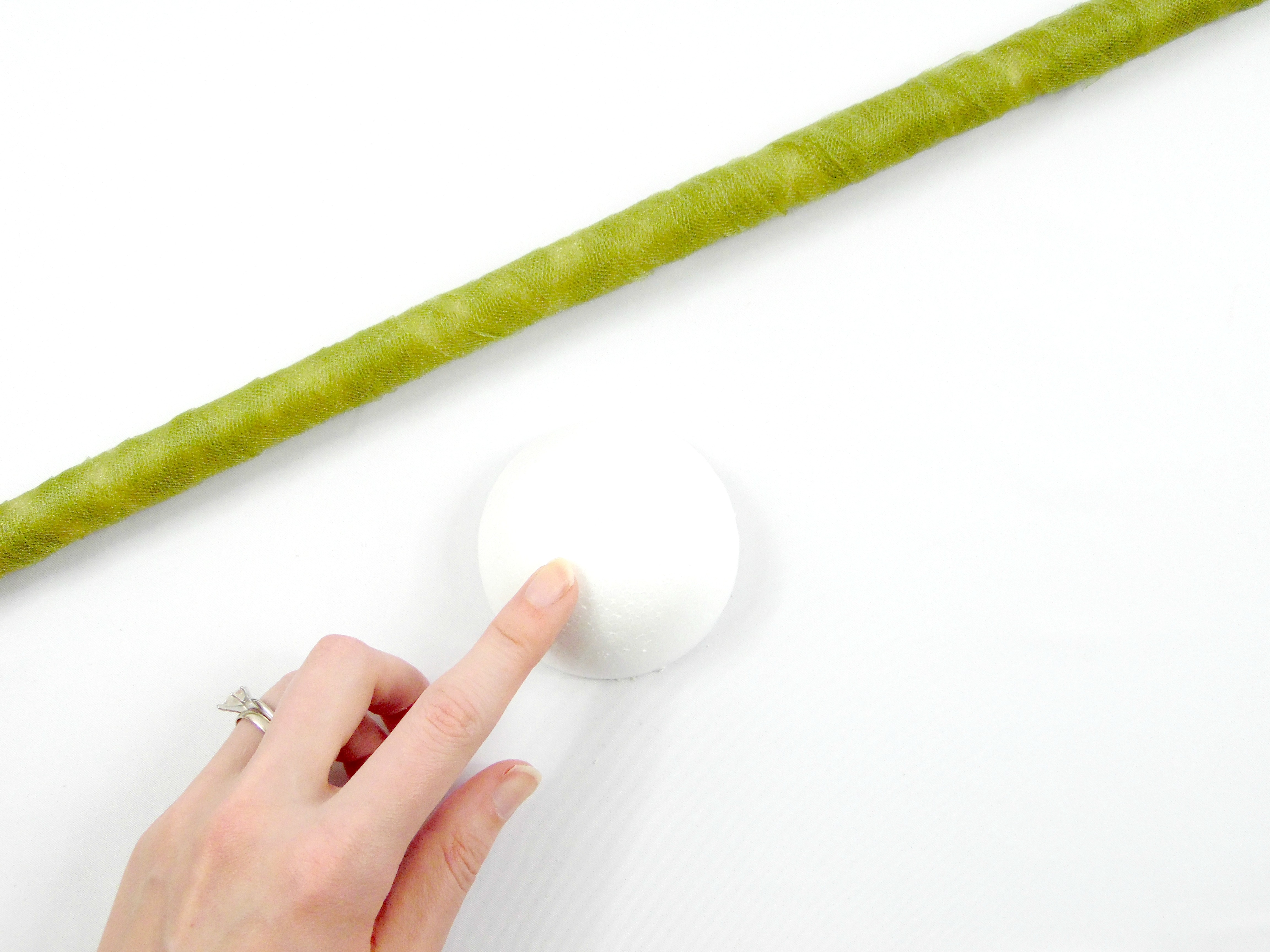 The giant paper flower stem has been wrapped in tulle and glued in place. The next step will involve white foam balls cut in half. 