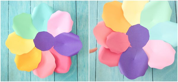 These two pictures show the progression of large rainbow flowers. The left picture shows the first layer of rainbow-colored paper petals around a purple base. The second photo is a closeup of a second layer added. 
