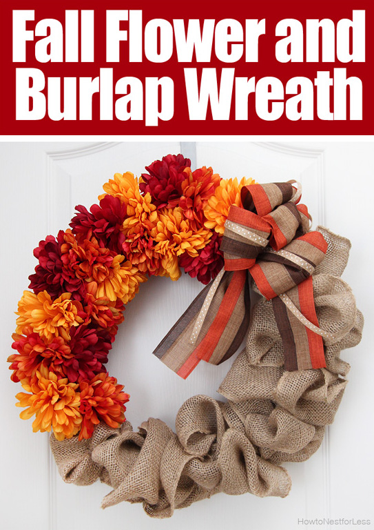 A DIY fall wreath hangs on a white door. The wreath has made with half faux flowers in burnt orange, marigold, and red colors, and half from burlap fabric.