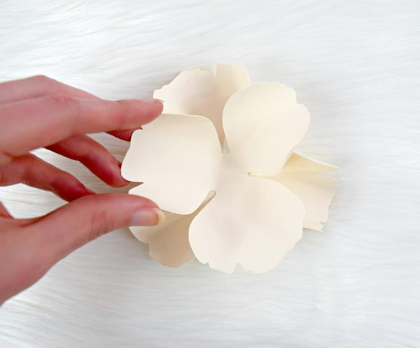 Abbi Kirsten gently adds one three-pointed white paper petal to the center of another one to begin making the Bella rose center bud. 