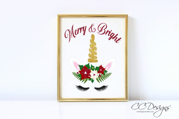 FREE Reindeer Cut File & Poinsettia Template can be altered to include a golden horn and unicorn ears. The text is above the image in red script and reads "Merry and Bright." The picture is in a gold frame. 
