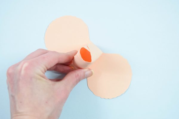 The DIY Rose paper flower rosebud is held by Abbi Kirsten, while the next layer of petals is seen below. 