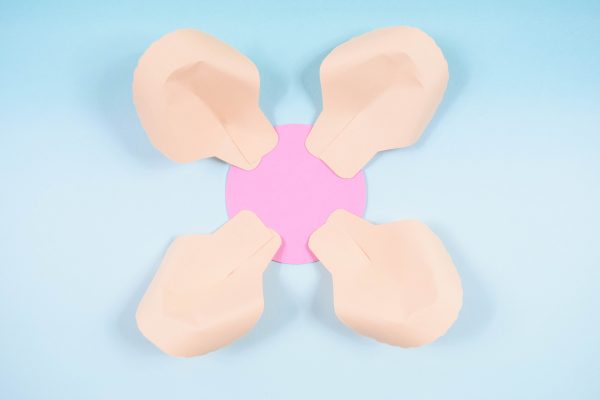 Four paper rose petals have been glued around a pink paper circle laying on a blue background. This is the base and outer layer of the DIY paper rose serena flower.
