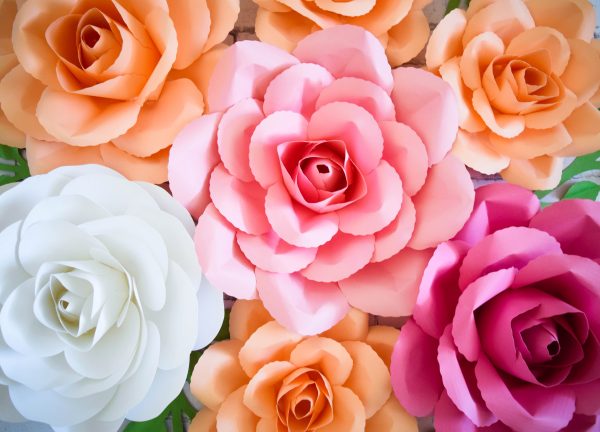 A closeup of a bouquet of DIY paper roses as seen from above. The flowers are white, orange, and pink.