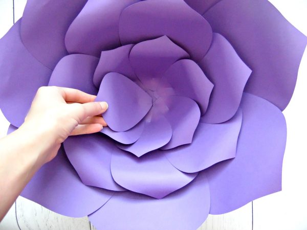 Abbi's hand reaches into the giant paper flower to add the final purple petal in the inner third layer. 