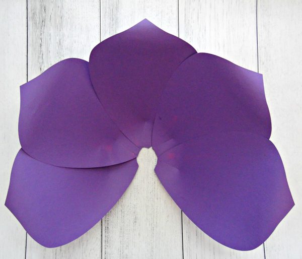 Five purple paper petals have been assembled and glued together to form the outer layer of a giant paper flower. Abbi Kirsten has many giant paper flower templates that can be used for holidays or home decor. 