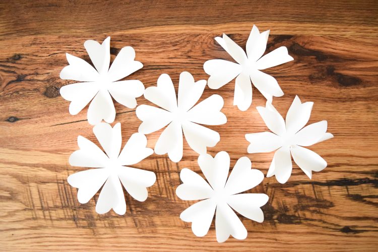 Six white paper flowers, which will be layered to make a single pomander paper flower ball.