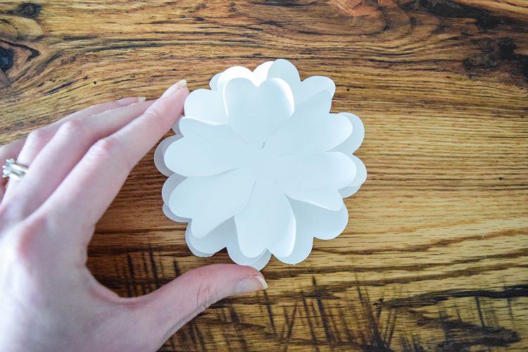 Multiple layers of white paper flower petals layered to become a pomander paper flower ball.