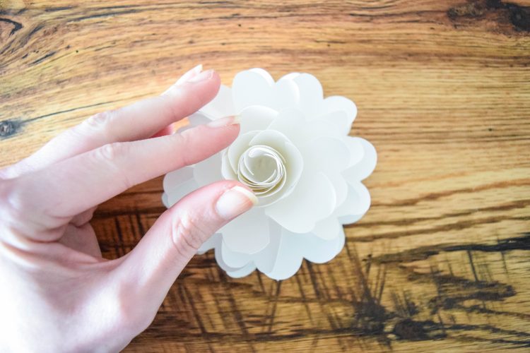 Abbi adds more layers to the pomander flower ball, rolled up in the center of the other paper flower layers.