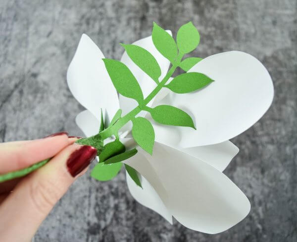 Green paper greenery cut with a cutting machine, attached to the stem of a white Magnolia Paper Flower.