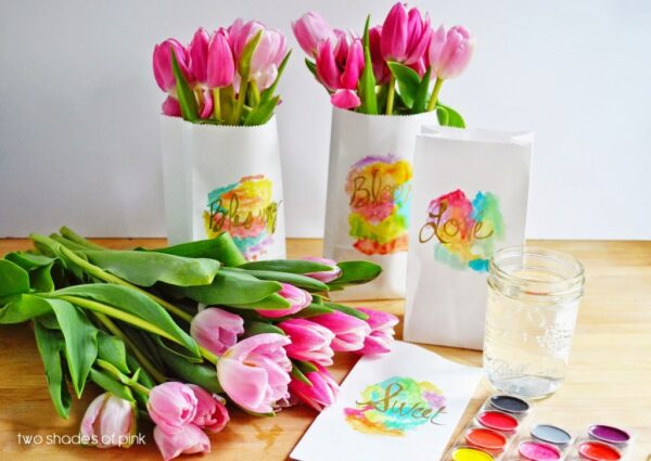 White paper bags with multi-colored paints on front filled with tulips
