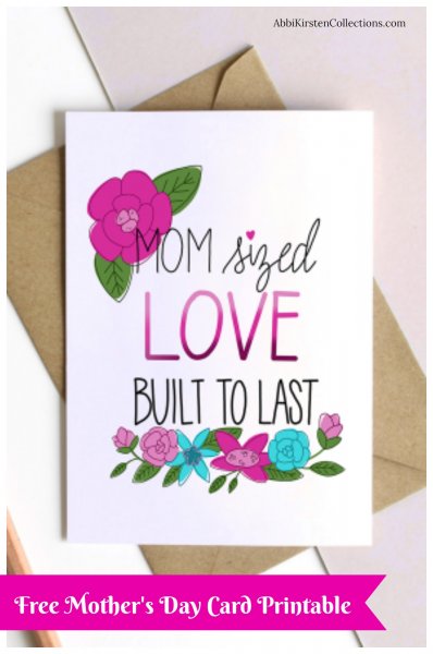 A white Mother's Day card with pink and black text along with bright pink and turquoise flowers. The card lays on a brown envelope. 